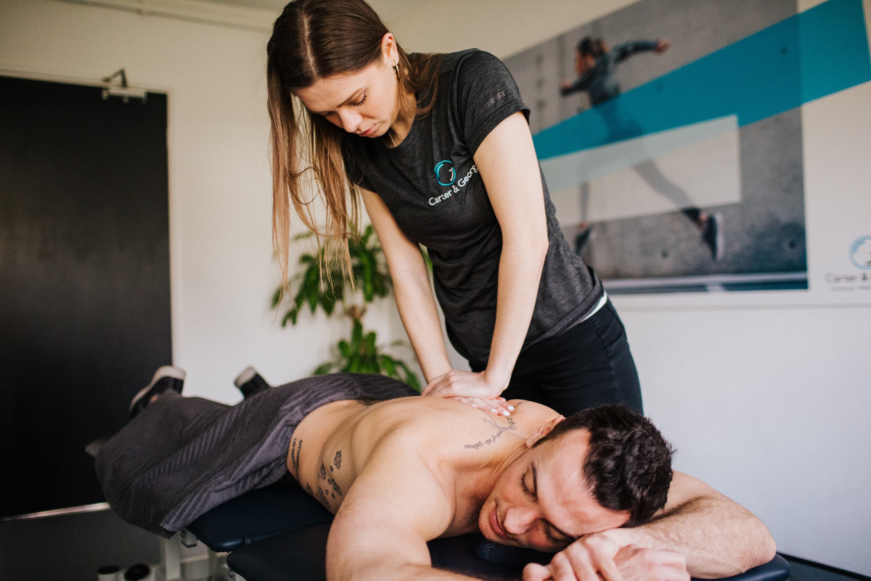 A massage therapist performs a back massage on a man lying face down on a table in a therapy room in Radlett.